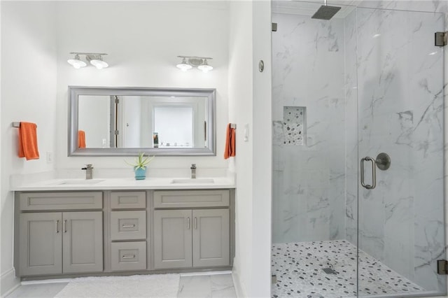 bathroom with double vanity, marble finish floor, a marble finish shower, and a sink