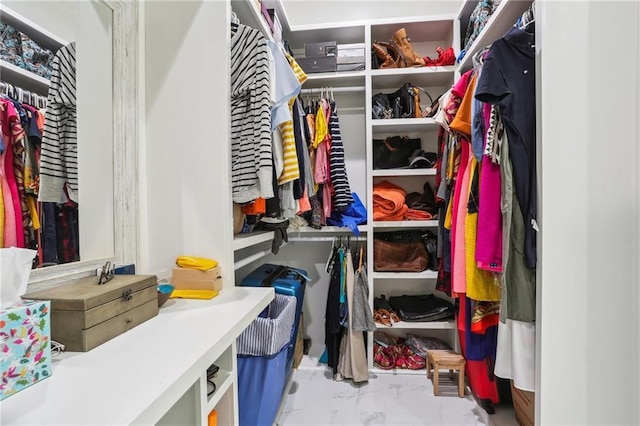 walk in closet featuring marble finish floor