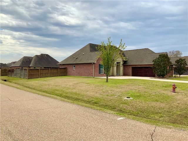 view of front of property featuring driveway, a garage, fence, a front lawn, and brick siding