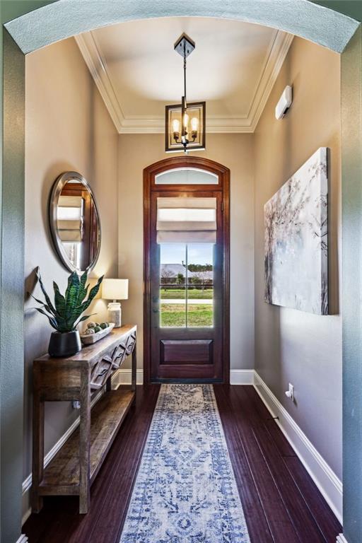 entrance foyer with a notable chandelier, wood-type flooring, baseboards, and ornamental molding