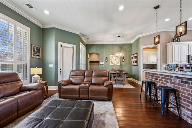 living room featuring visible vents, crown molding, baseboards, a chandelier, and dark wood-style floors