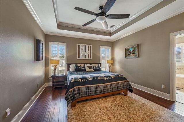 bedroom with hardwood / wood-style floors, a raised ceiling, multiple windows, and visible vents