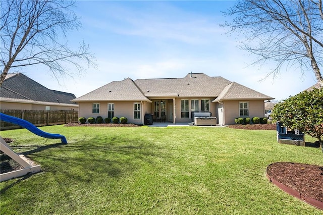 back of property with a lawn, a shingled roof, a patio, and fence