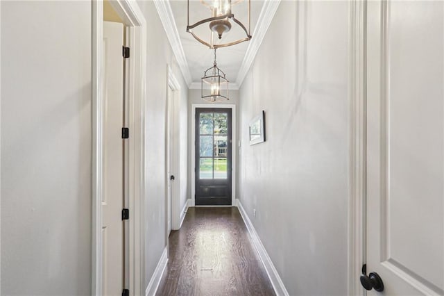 entryway with dark wood-type flooring, a notable chandelier, crown molding, and baseboards