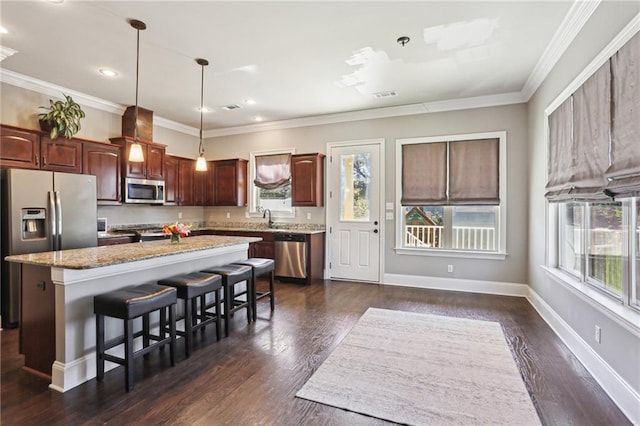 kitchen featuring stainless steel appliances, a breakfast bar, a center island, and baseboards