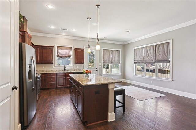 kitchen featuring visible vents, dark wood finished floors, a kitchen island, appliances with stainless steel finishes, and ornamental molding