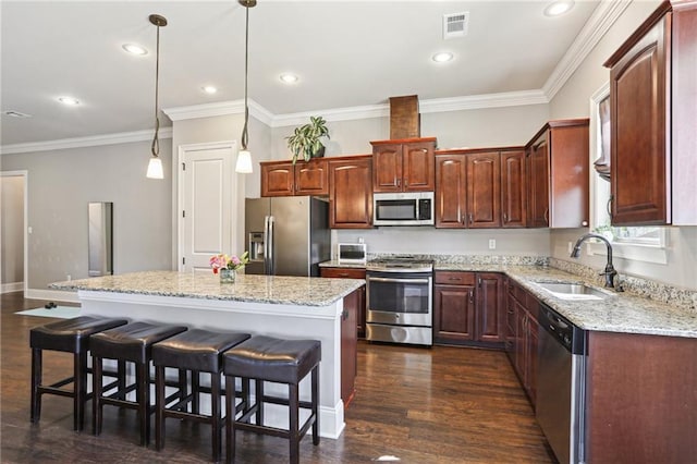 kitchen with dark wood-style floors, a center island, visible vents, appliances with stainless steel finishes, and a sink