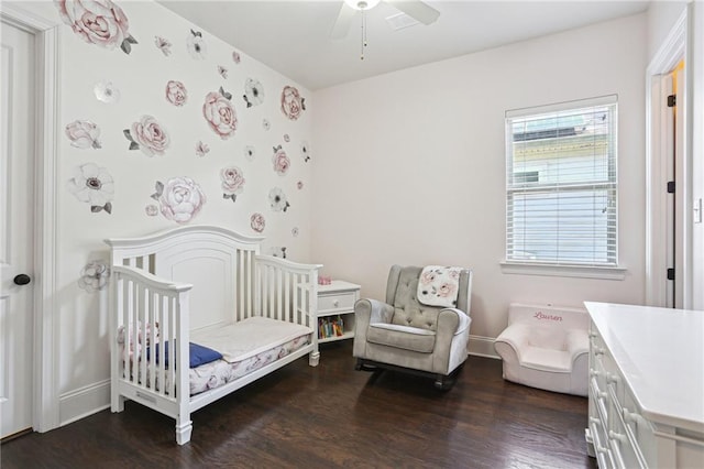 bedroom with a crib, ceiling fan, baseboards, and wood finished floors