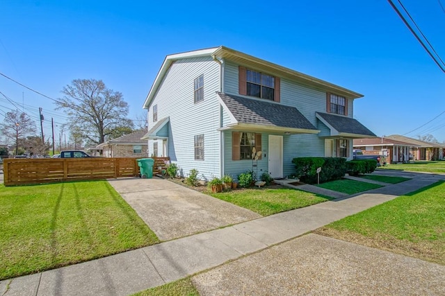 view of front of home featuring roof with shingles, fence, and a front yard