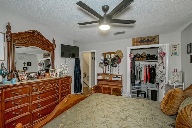 bedroom featuring a closet, visible vents, a ceiling fan, a textured ceiling, and wood finished floors