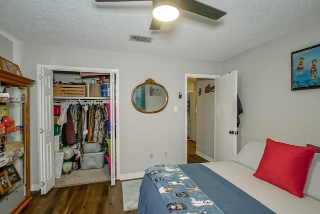 bedroom featuring a textured ceiling, ceiling fan, wood finished floors, visible vents, and a closet