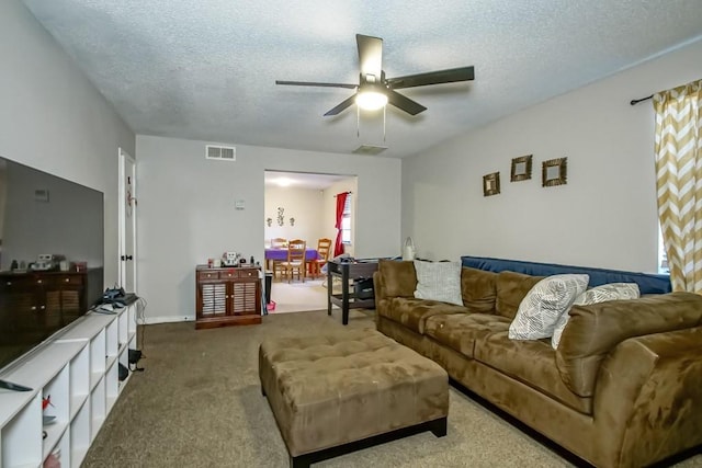 living room featuring carpet, visible vents, a ceiling fan, a textured ceiling, and baseboards