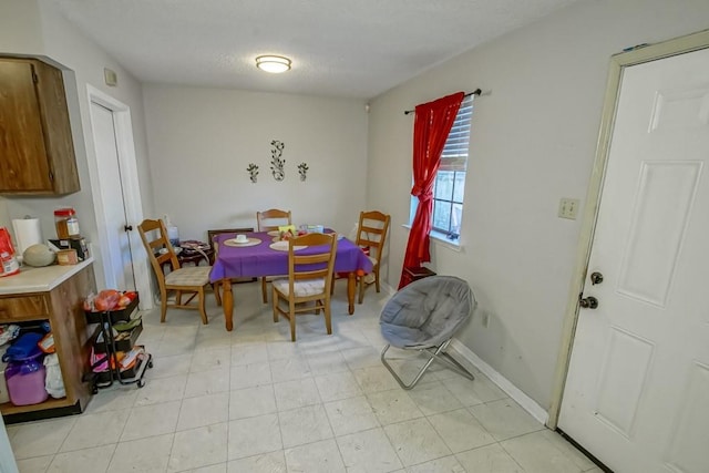 dining space with baseboards and a textured ceiling