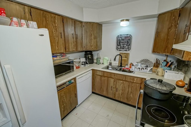 kitchen with white appliances, a textured ceiling, light countertops, and a sink