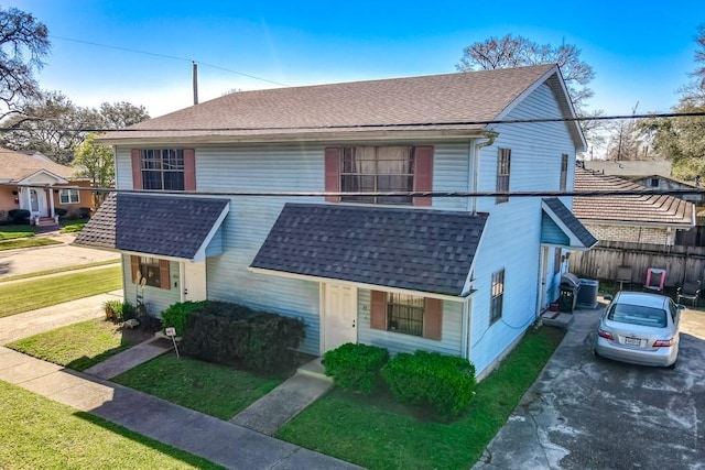 view of front of house featuring roof with shingles, fence, and driveway