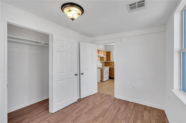 unfurnished bedroom with light wood-type flooring, baseboards, visible vents, and a closet