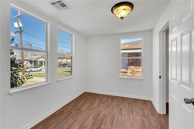 unfurnished room with baseboards, visible vents, and wood finished floors