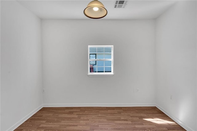 spare room with visible vents, baseboards, and wood finished floors