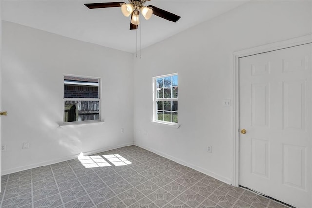 spare room featuring light floors, a ceiling fan, and baseboards