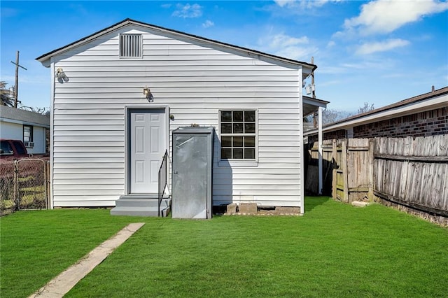 rear view of house with crawl space, a lawn, and fence