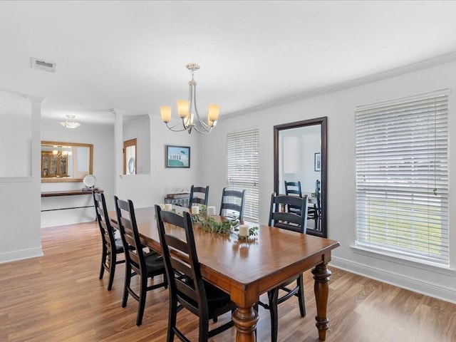 dining area with light wood-style flooring, a notable chandelier, visible vents, baseboards, and ornamental molding