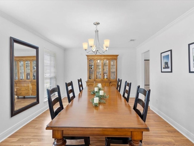 dining space featuring a notable chandelier, visible vents, light wood-style floors, ornamental molding, and baseboards