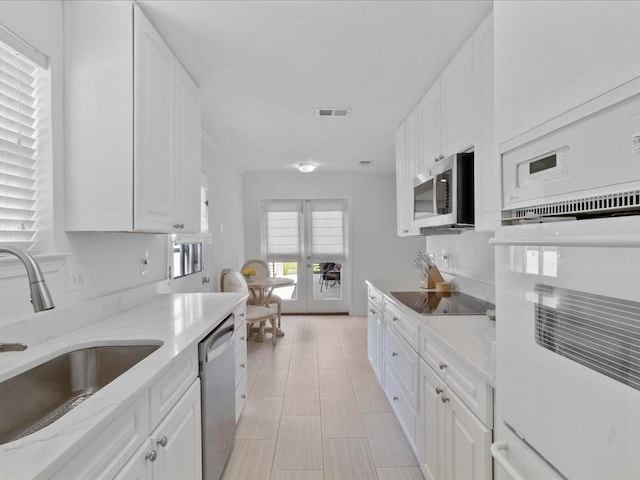 kitchen featuring visible vents, appliances with stainless steel finishes, white cabinetry, a sink, and light stone countertops