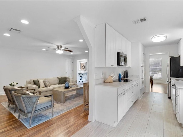 kitchen with light countertops, stainless steel microwave, and visible vents