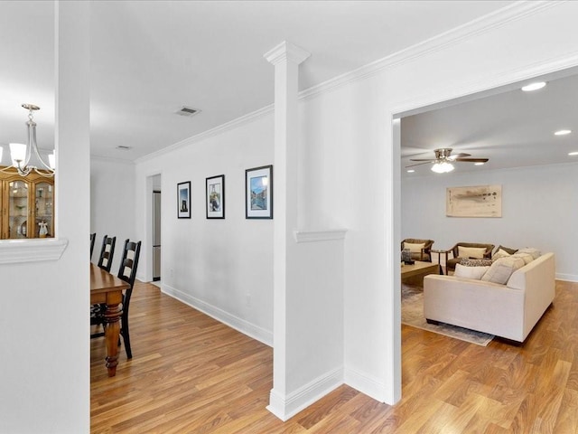 corridor featuring baseboards, visible vents, crown molding, and light wood finished floors