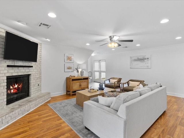 living room featuring baseboards, a fireplace, visible vents, and wood finished floors