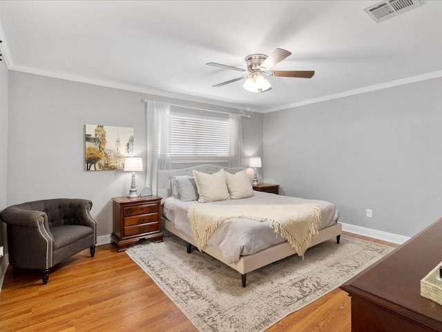 bedroom featuring baseboards, ornamental molding, visible vents, and light wood-style floors