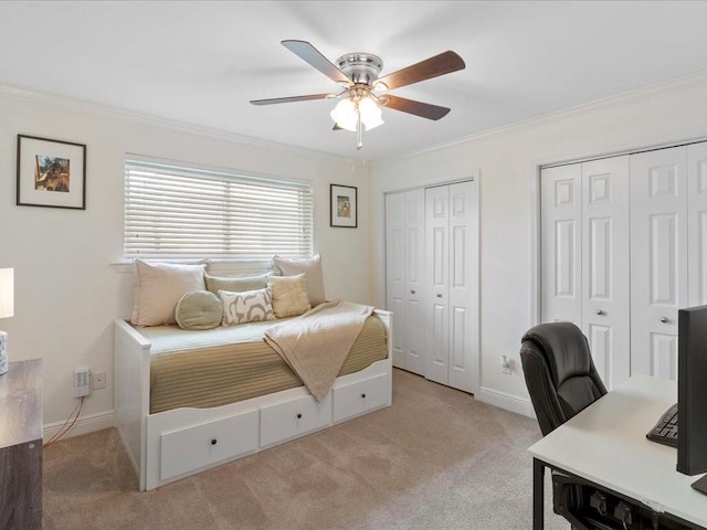 bedroom with light carpet, baseboards, ornamental molding, and multiple closets