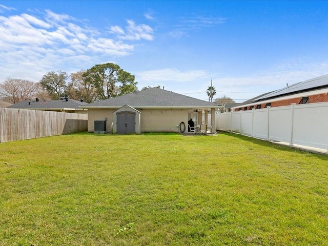 back of house featuring a yard, central AC unit, and a fenced backyard