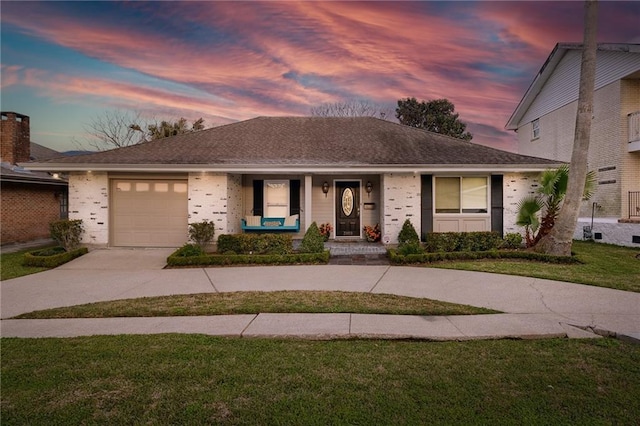 single story home featuring an attached garage, covered porch, concrete driveway, a yard, and roof with shingles