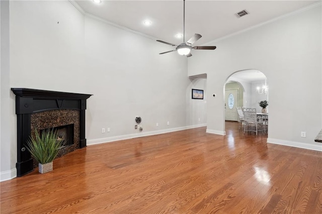 living area with arched walkways, visible vents, a ceiling fan, a high end fireplace, and wood finished floors