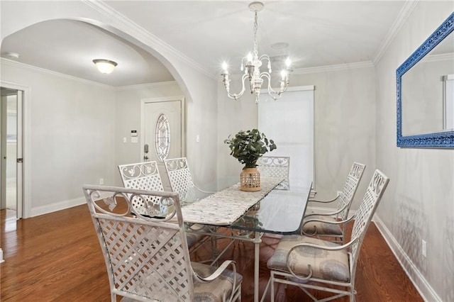 dining area with baseboards, arched walkways, wood finished floors, and ornamental molding