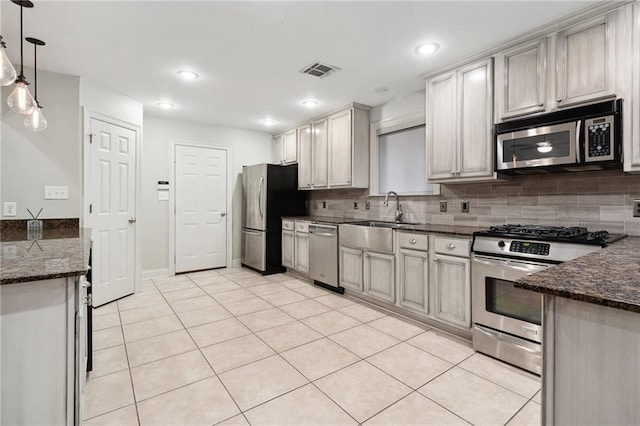 kitchen featuring light tile patterned floors, stainless steel appliances, a sink, visible vents, and tasteful backsplash