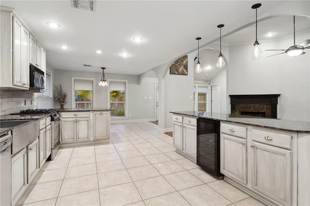 kitchen with light tile patterned floors, stainless steel appliances, tasteful backsplash, visible vents, and beverage cooler