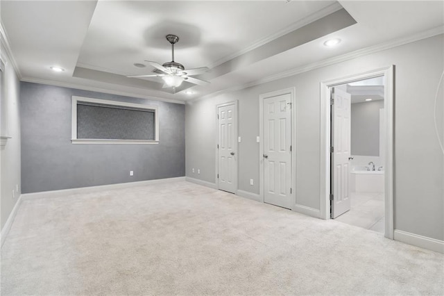 unfurnished bedroom featuring baseboards, ornamental molding, a tray ceiling, carpet, and ensuite bath