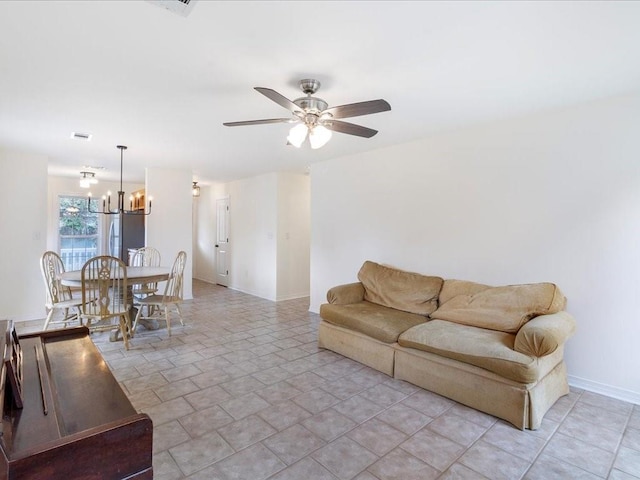 living area with baseboards and ceiling fan with notable chandelier