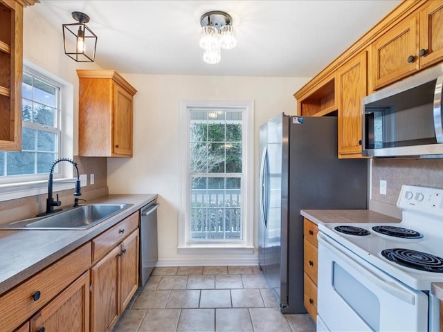 kitchen featuring stainless steel appliances, brown cabinetry, a sink, and baseboards