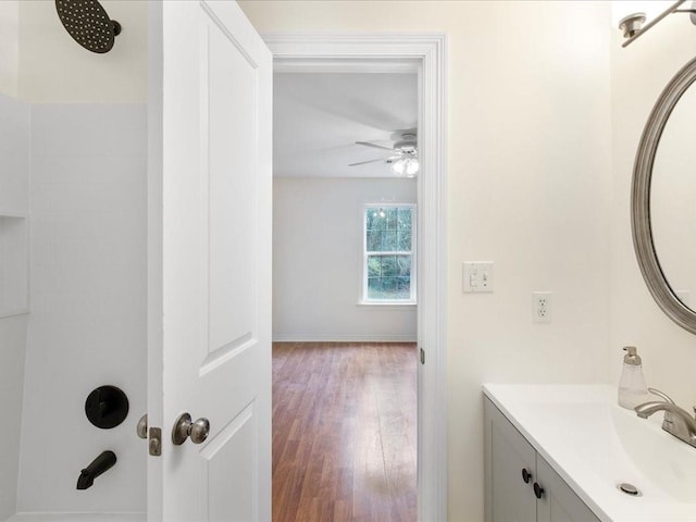 bathroom with ceiling fan, wood finished floors, vanity, baseboards, and a shower