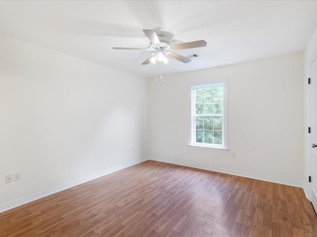 empty room with ceiling fan, baseboards, and wood finished floors