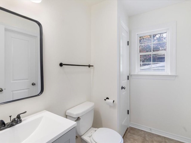 half bath featuring tile patterned flooring, baseboards, vanity, and toilet