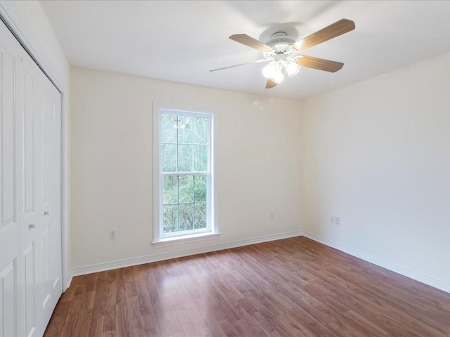 unfurnished bedroom with a closet, wood finished floors, a ceiling fan, and baseboards