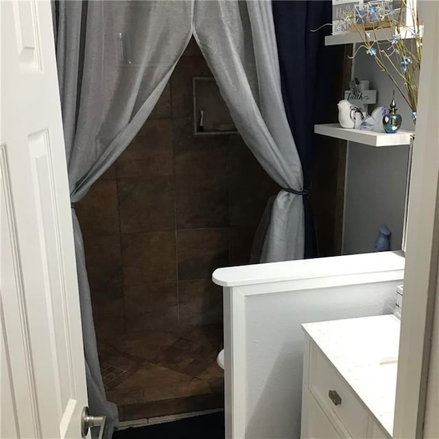 bathroom featuring a tile shower and vanity