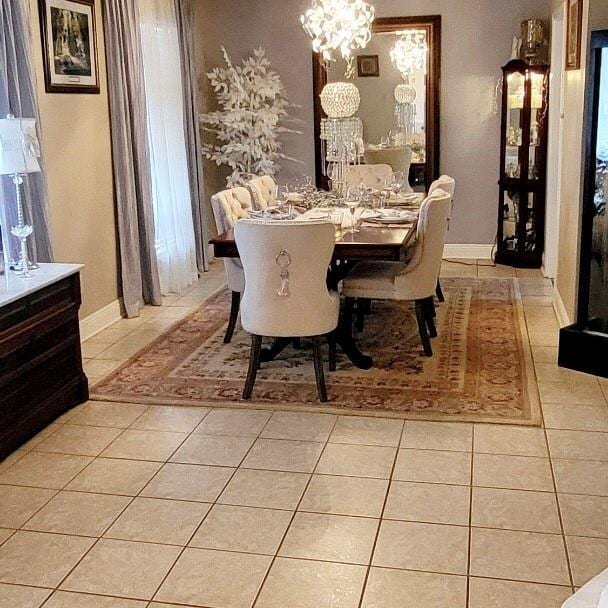 dining space featuring baseboards, a notable chandelier, and light tile patterned floors