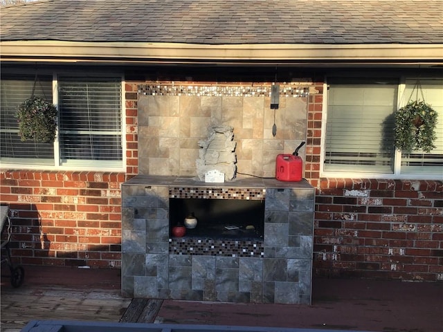 exterior details with roof with shingles and brick siding