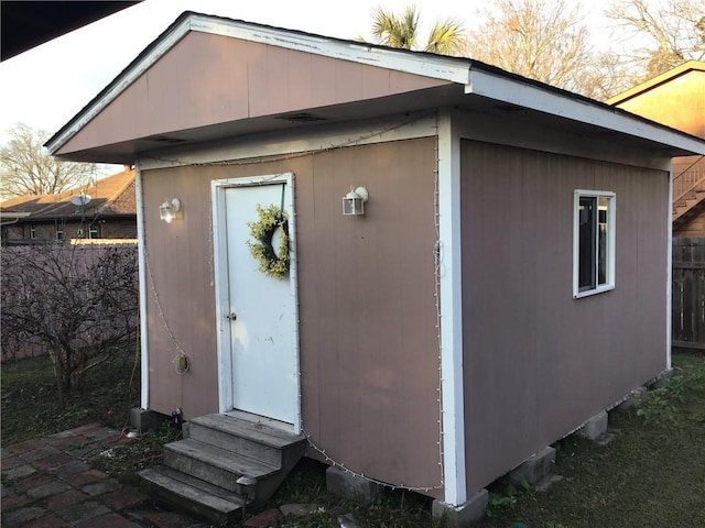 view of outbuilding featuring entry steps, fence, and an outbuilding