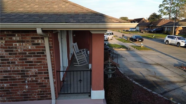 details with gutters, a downspout, a shingled roof, and brick siding